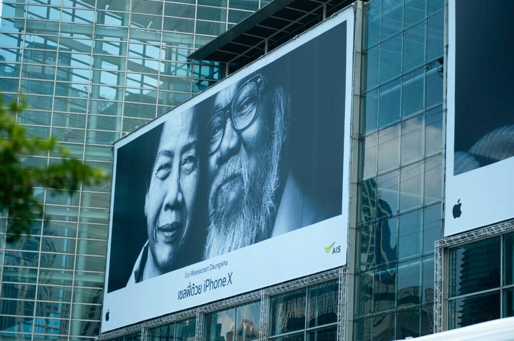 Looking at a city billboard of an iPhoneX advertisement of a couple in their 50s smiling.
